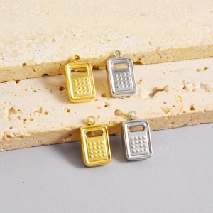 Macro detail of stainless steel grater pendants in gold and silver on stone tray