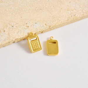 Golden calculator pendant charm in stainless steel for DIY jewelry on stone background