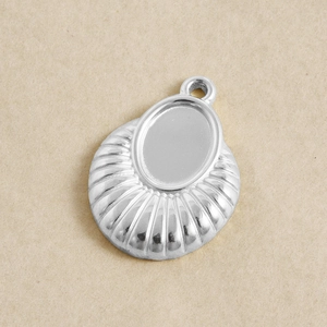 Macro detail of a silver oval pendant base with fan-shaped texture for DIY jewelry making