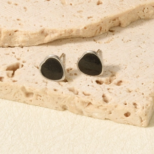 Close-up of heart-shaped stainless steel earrings with black enamel inlay on stone