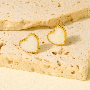 Dettaglio di orecchini a cuore dorati con smalto avorio e delicato bordo perlato