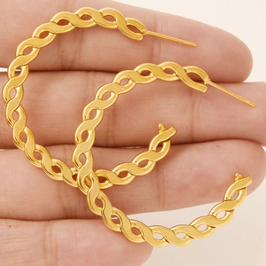 Unique gold braided stainless steel hoop earrings held by hand for size reference