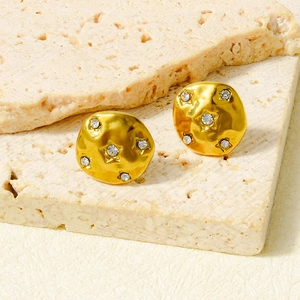 Detailed view of gold plated round earrings with hammered texture and star zircon inlay