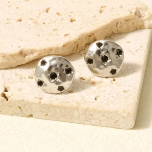 Detailed macro view of silver earrings with black stones and hammered texture finish