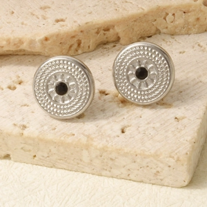 Macro shot of vintage silver earrings with black gemstones and intricate sunray engravings
