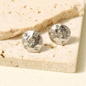Close-up of irregular silver-toned stud earrings with star-shaped zircon inlays on stone