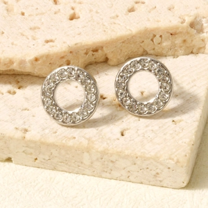Macro shot of silver paved rhinestone round hollow stud earrings on beige stone texture