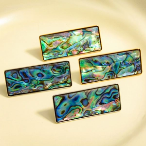 Detalle de incrustación de abulón en pendientes rectangulares geométricos de oro y plata