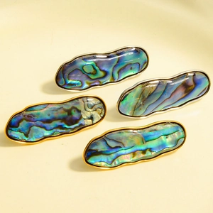 Vista macro de pendientes geométricos de lágrima con incrustación de concha de abulón