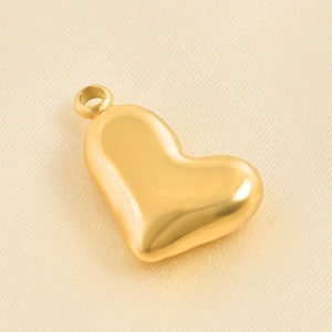 Macro shot of matte gold heart pendant made of stainless steel on silk fabric background