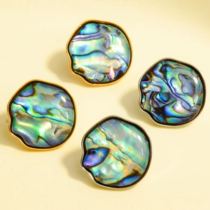 Detalle de pendientes de concha de abulón natural con marcos irregulares en oro y plata