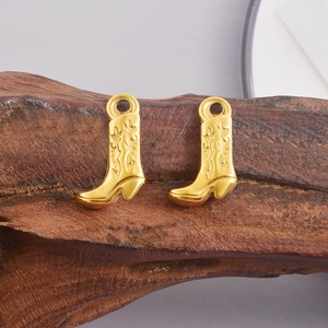 Dettaglio macro dei ciondoli a stivale da cowboy in acciaio inox 304 con motivi vintage