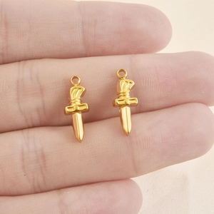 Paire de pendentifs dagues en acier inoxydable doré, tenus pour montrer la taille