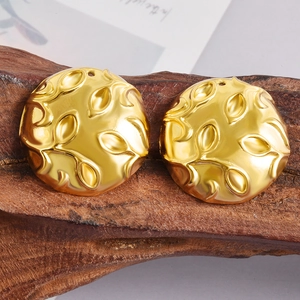 Macro shot of gold-plated leaf embossed round pendants on a rustic wood surface