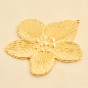 Makroaufnahme von 18k vergoldetem Blumenanhänger mit radialer Textur und Blütenstempel