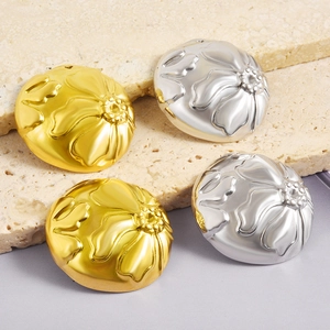 Macro detail of round floral embossed metal pendants in gold and silver finishes