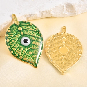 Colgante de hoja esmaltada verde con ojo malvado y vetas doradas sobre fondo de piedra