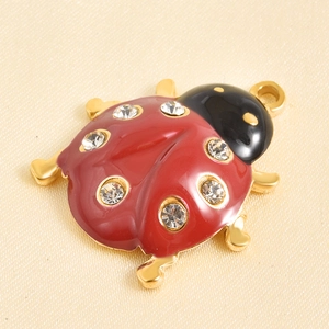 Macro di un ciondolo coccinella rossa con zirconi bianchi e dettagli in oro lucido