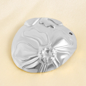 Detailed macro of a silver S925 floral embossed round pendant on champagne silk fabric