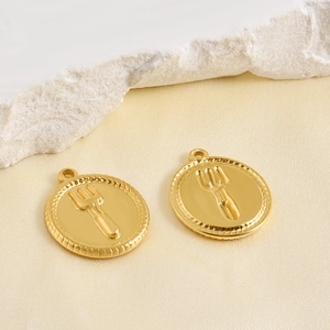 Detailweergave van ronde gouden hangers met vorkmotief op een elegante zijden achtergrond