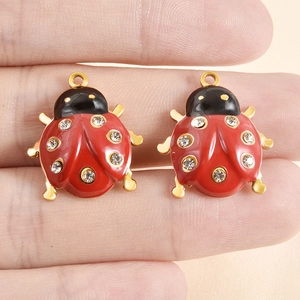 Coppia di ciondoli a coccinella in smalto rosso con strass e base in metallo dorato