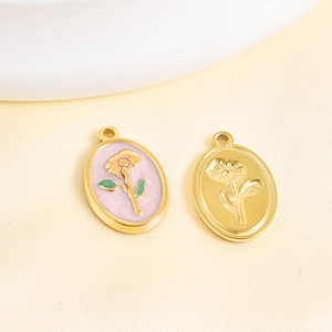 Detailed macro view of two oval flower pendants with pink enamel and gold relief finishes