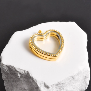 Detail of a gold heart locket with sparkling zircon border on a white stone base