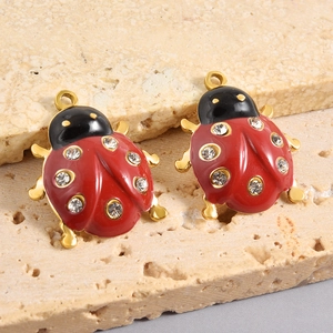 Dettaglio dei ciondoli a coccinella con smalto rosso e strass luccicanti su base dorata
