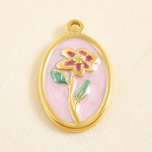 Macro shot of gold stainless steel oval pendant with pink enamel and violet flower detail
