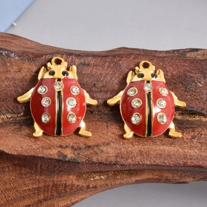 Dettaglio di due ciondoli coccinella rossi con strass su base di legno naturale