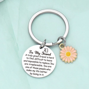 Close-up of stainless steel friendship keychain with pink daisy charm and engraved message
