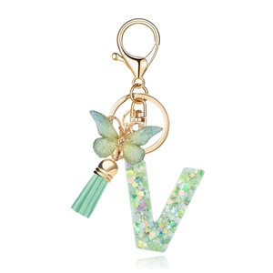Detail of resin letter V keychain with green glitter, butterfly charm and mint tassel