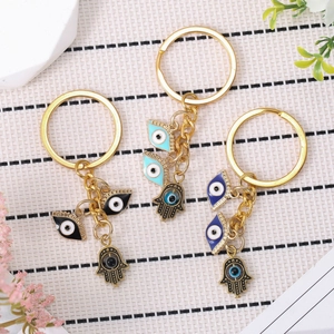Golden Evil Eye and Hamsa Hand keychain set with colorful enamel charms in lifestyle setting