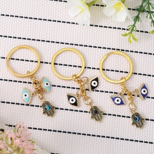 Golden Hamsa Hand and Evil Eye keychains in blue and black enamel with floral accents