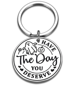 Detail of round stainless steel keychain with Halloween icons and engraved text