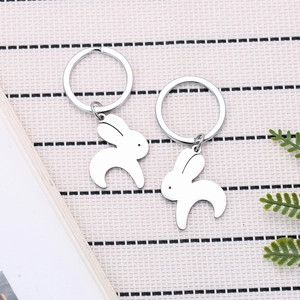 Minimalist silver rabbit keychains with heart motif on woven texture background