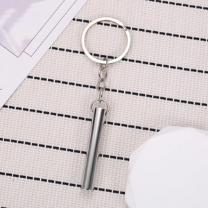 Polished silver stainless steel meditation whistle pendant with ring on minimalist background