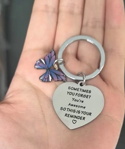 Detail of heart tag engraved with inspirational quote and colorful butterfly on keychain