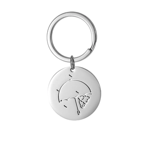 Macro shot of silver stainless steel round keychain with laser-engraved bear and umbrella