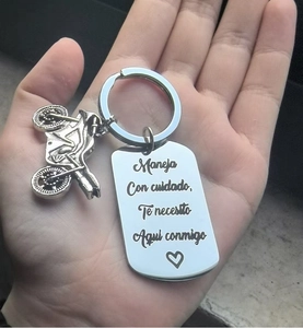 Macro shot of a stainless steel keychain with a motorcycle charm and Spanish engraving