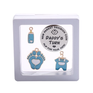 Detail of baby shower gift set featuring enamel charms and daddy's turn decision coin