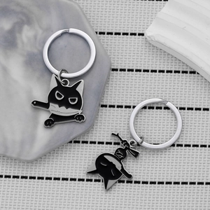 Close-up of black cartoon cat keychain and Kuromi-style metal pendant on marble tray