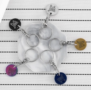 Detail of colorful stainless steel supermarket trolley token keychains on marble base