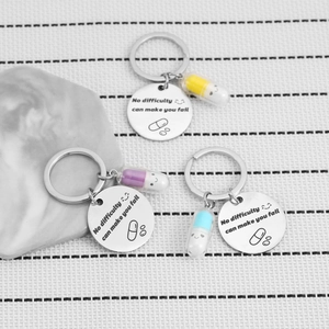 Stainless steel pill keychains with motivational quotes in yellow, purple, and blue colors
