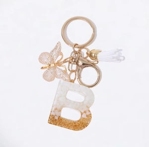 Portachiavi bianco con nappa farfalla e ciondolo lettera B in resina glitterata oro