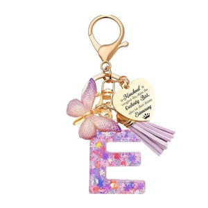 Détail macro du porte-clés lettre E en résine violette avec paillettes et papillon