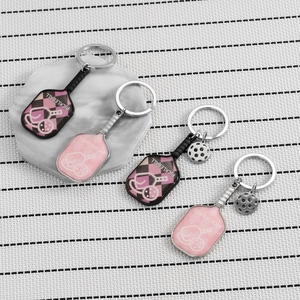 Pink and black zinc alloy pickleball paddle keychains with miniature ball pendants