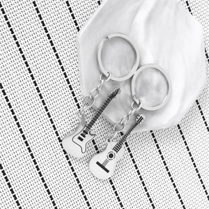 Polished stainless steel electric and acoustic guitar keychains on a white tray