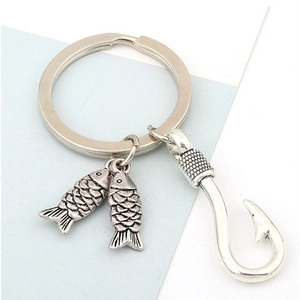 Vintage metal keychain with silver fish charms and a rustic fishhook pendant on blue background