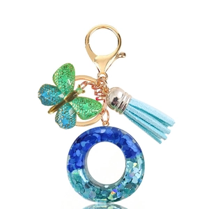 Detail of blue sequin resin ring keychain with butterfly charm and blue suede tassel
